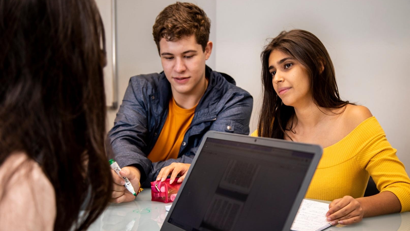 três alunos em aula fazendo anotações