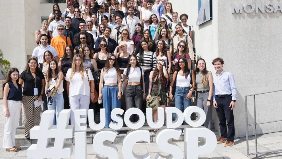 Imagem de um grupo de pessoas em frente a um prédio, com um letreiro "#EU SOU DO ISCCSP".