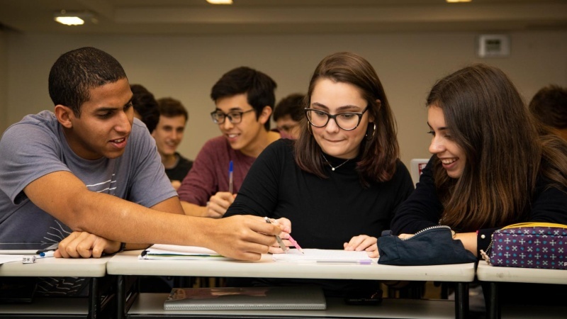 grupo de amigos sentados e estudando em sala de aula