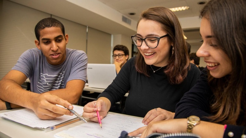 três alunos em aula ouvindo o professor falar