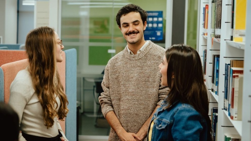 três alunos em pé conversando